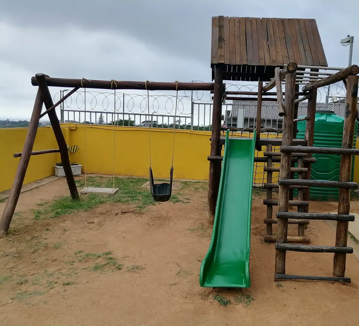 The outdoor playground at Lia's Montessori with swings, a slide and climbing equipment.